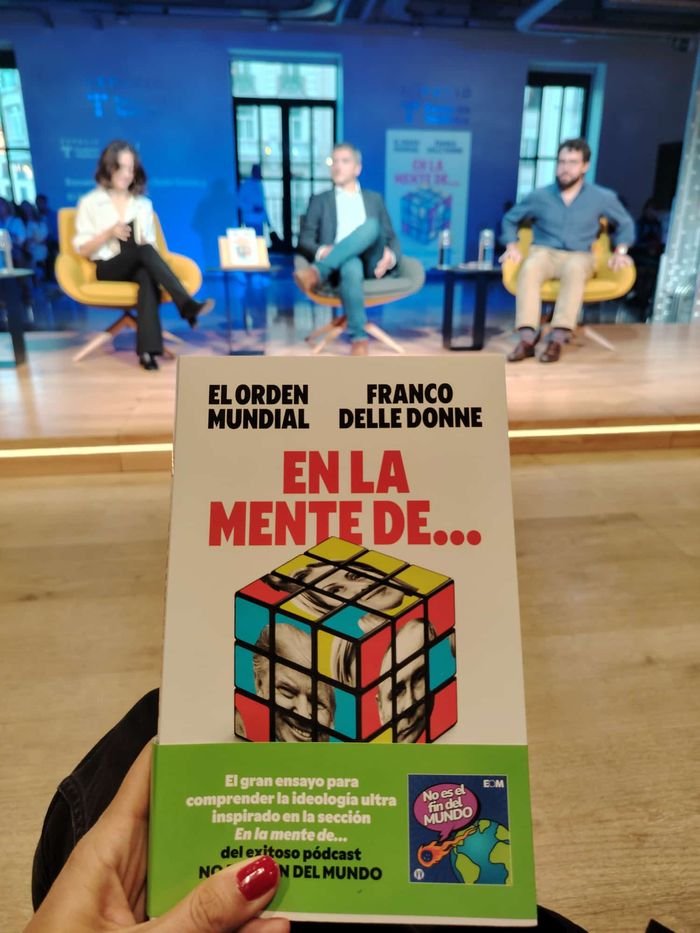 Un ejemplar de En la mente de… en primer plano y la charla en el escenario al fondo